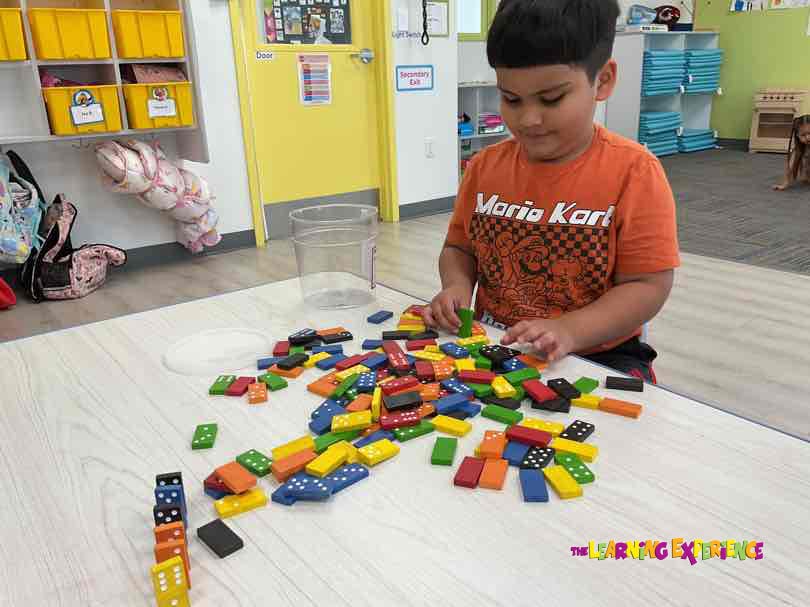 Child playing with colorful dominoes on a table