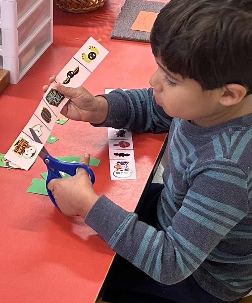 Child cutting out Halloween-themed paper shapes with scissors
