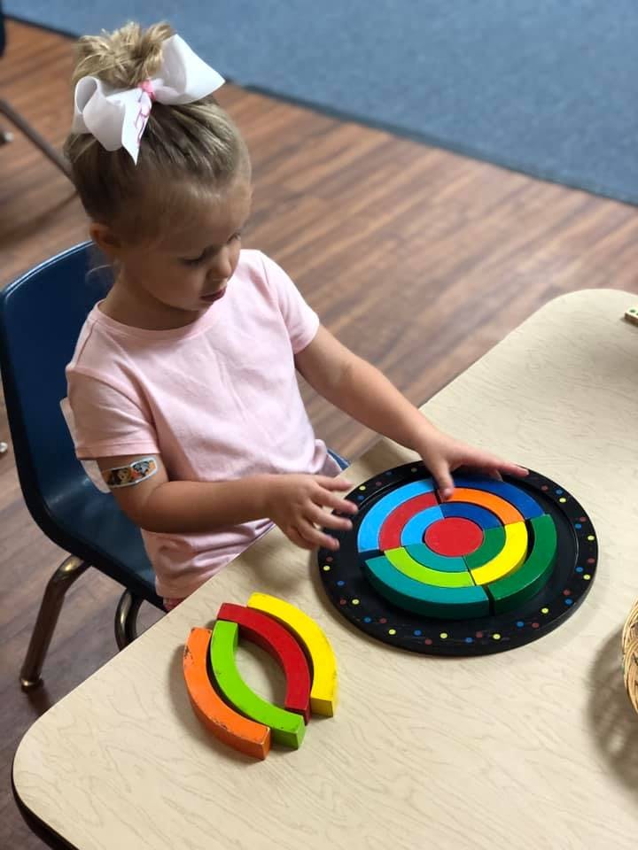 Child playing with a colorful circular puzzle on a table
