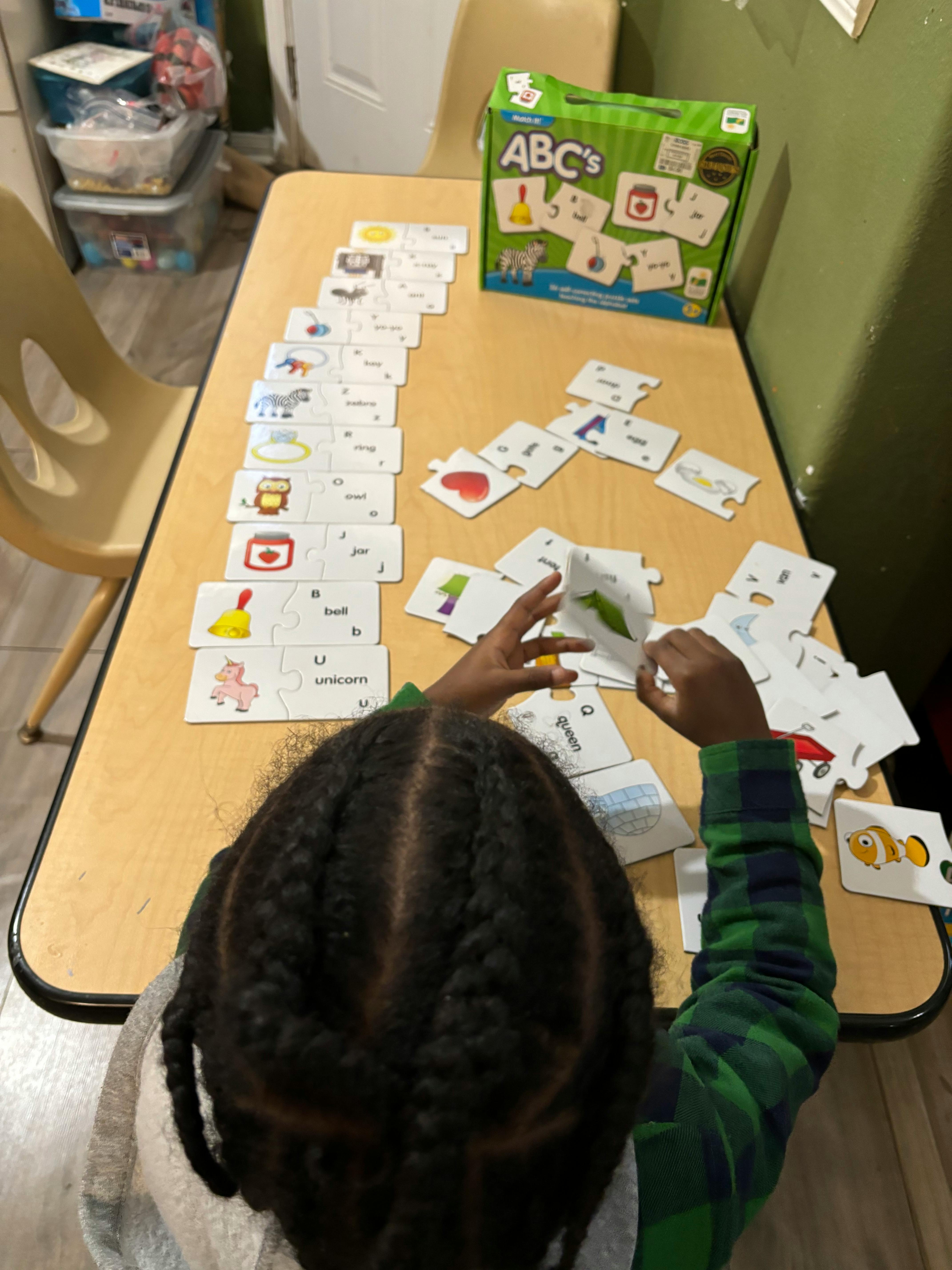 Child playing with ABC flashcards on a table