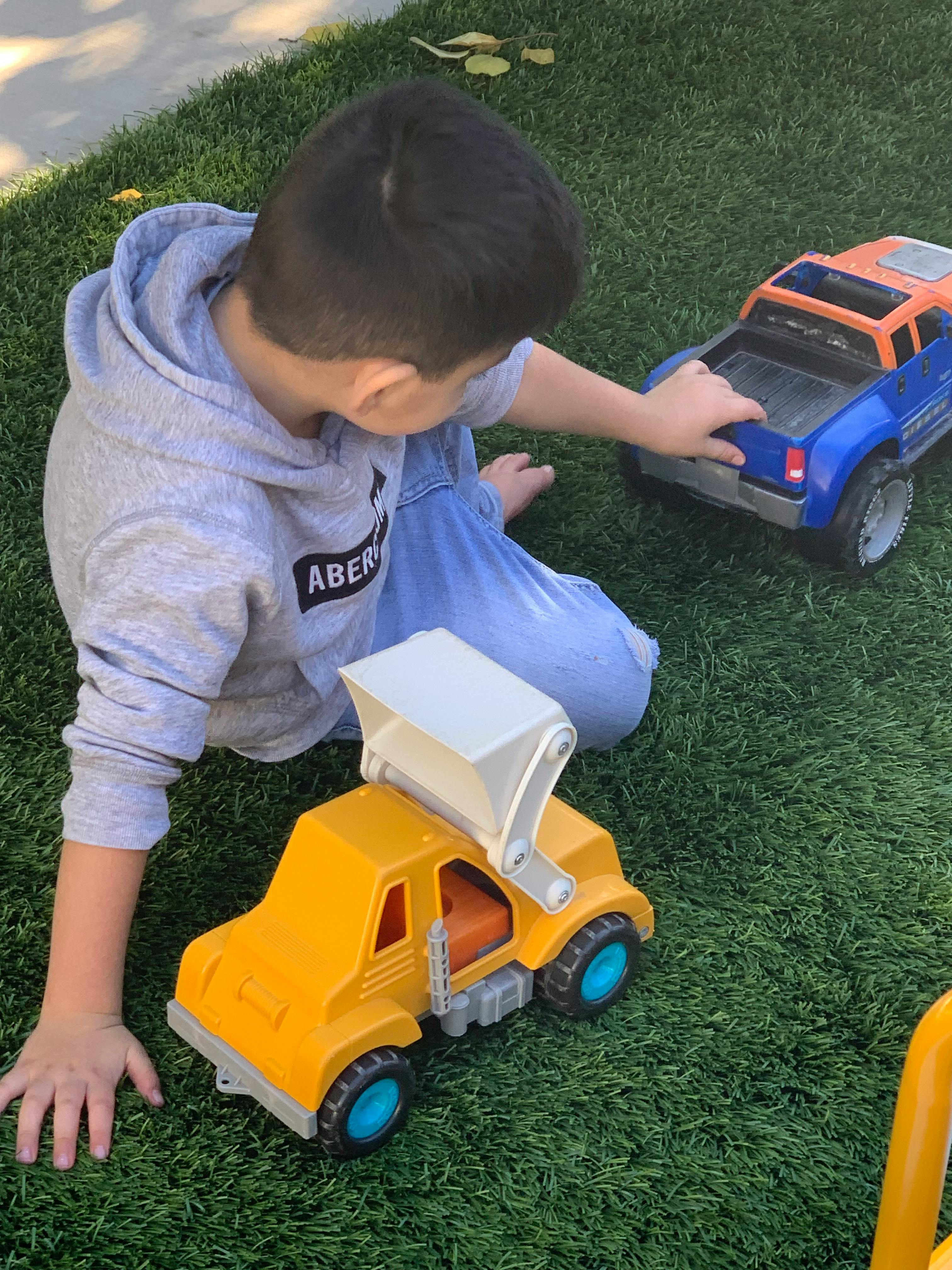 Child playing with toy trucks on grass