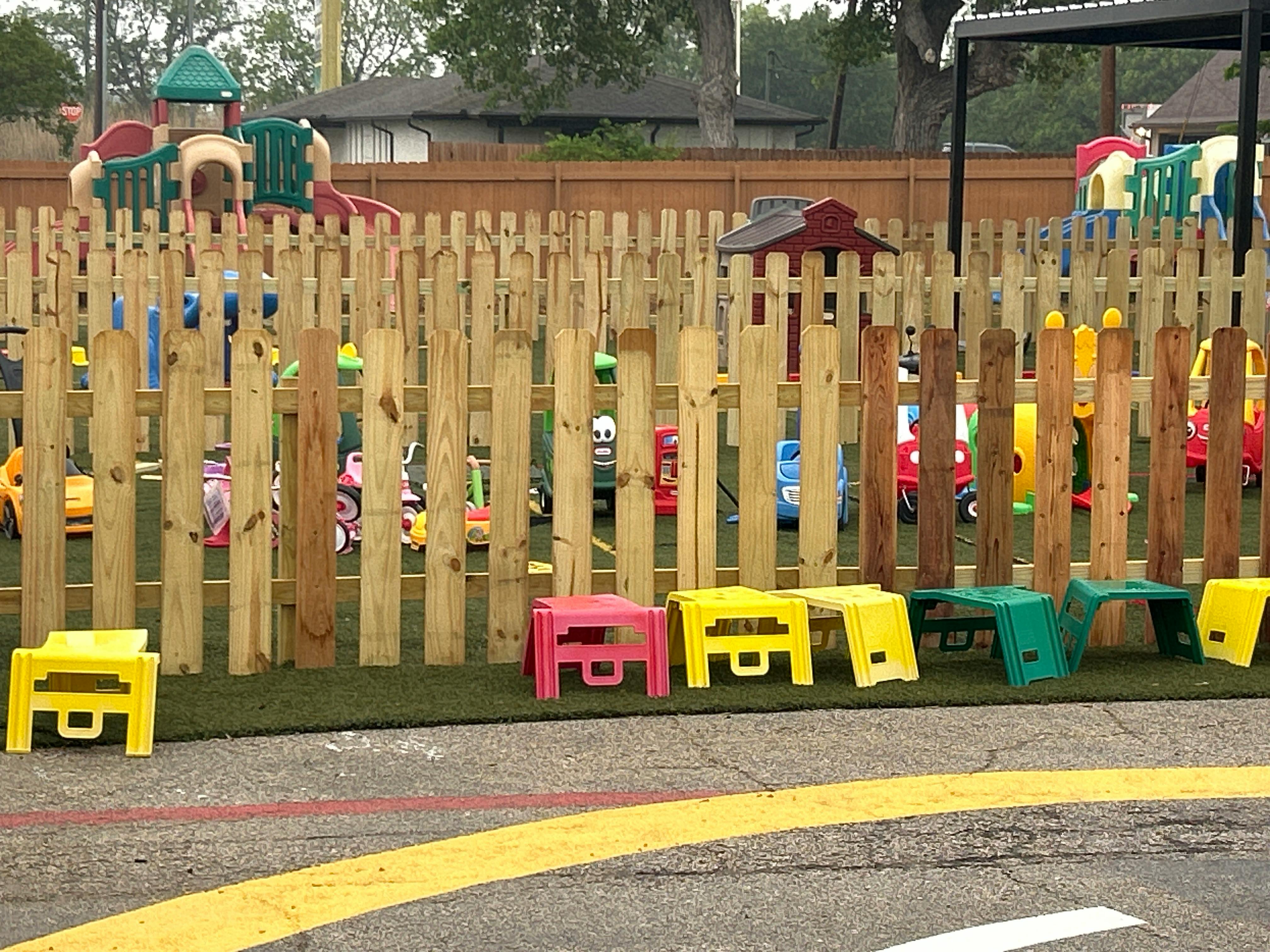 Wooden fence with colorful plastic stools in front of a playground