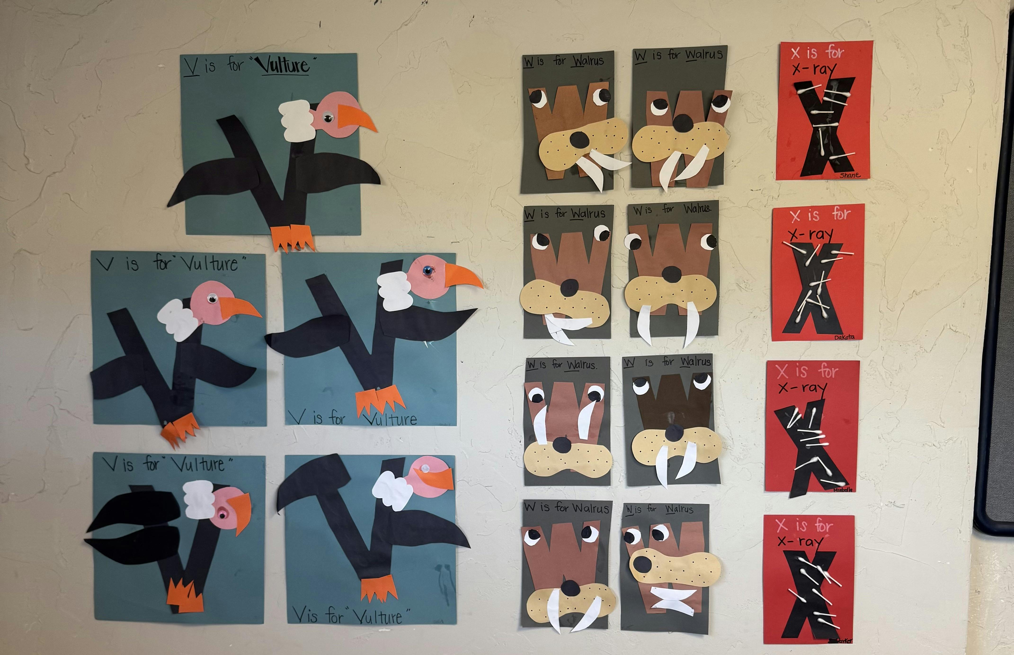 Children's alphabet craft projects displayed on a wall