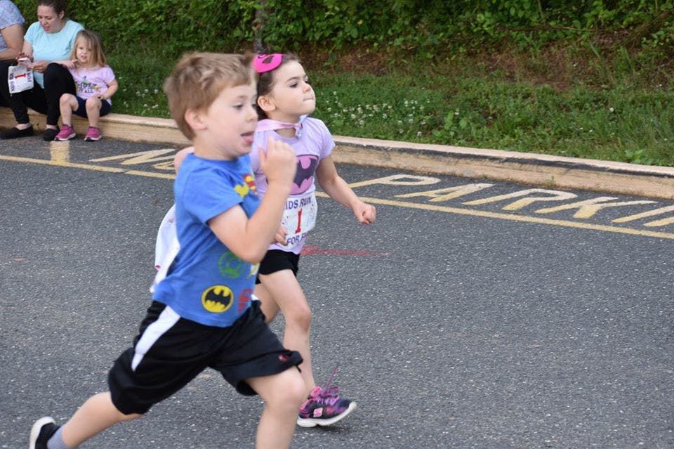 Two children running on a paved surface