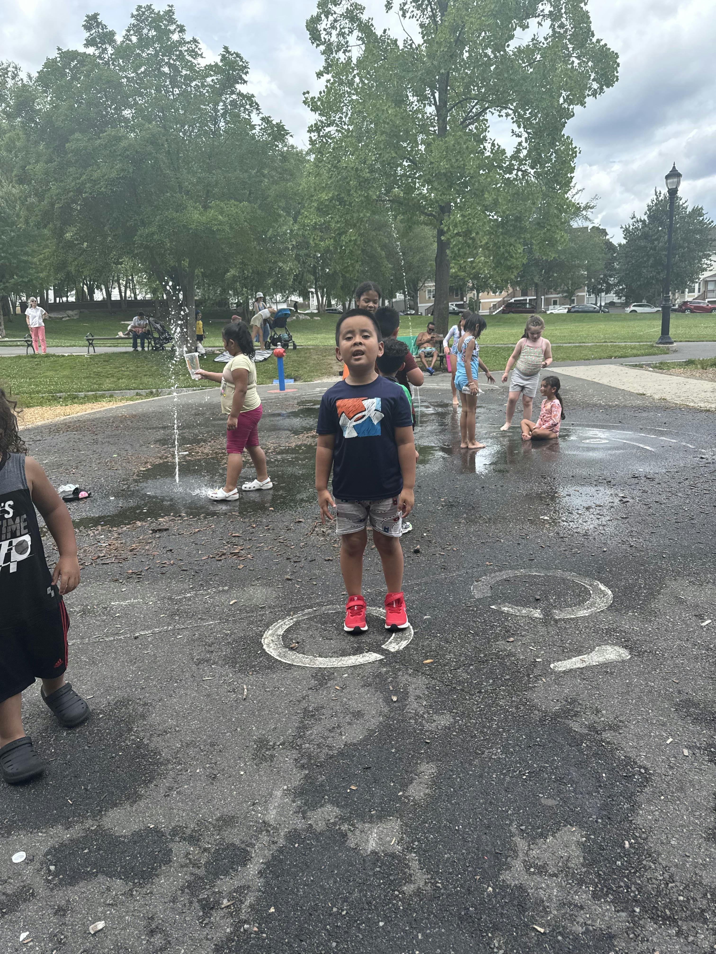 Child standing in water at a splash pad with other children