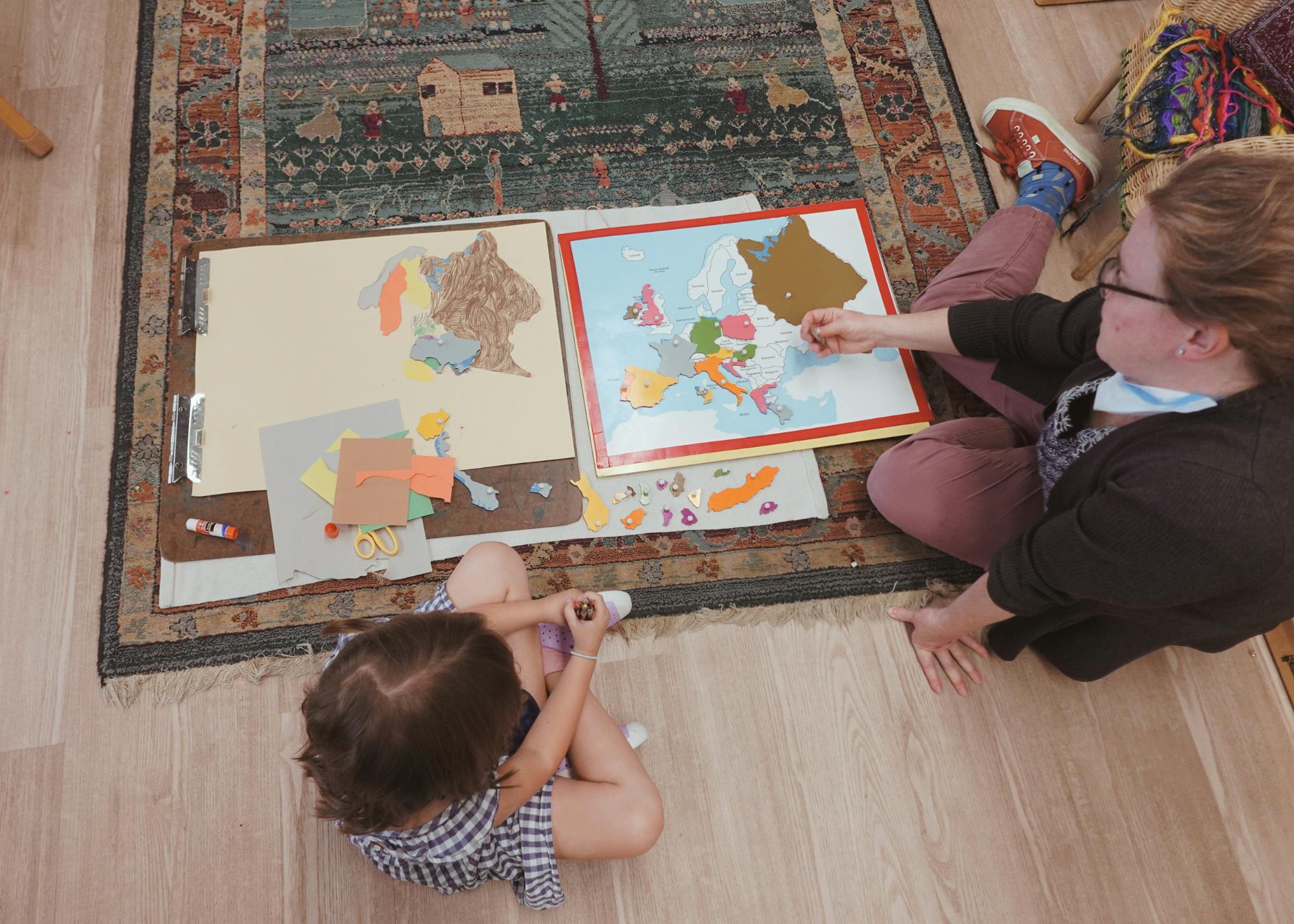 Person and child on floor assembling a puzzle map