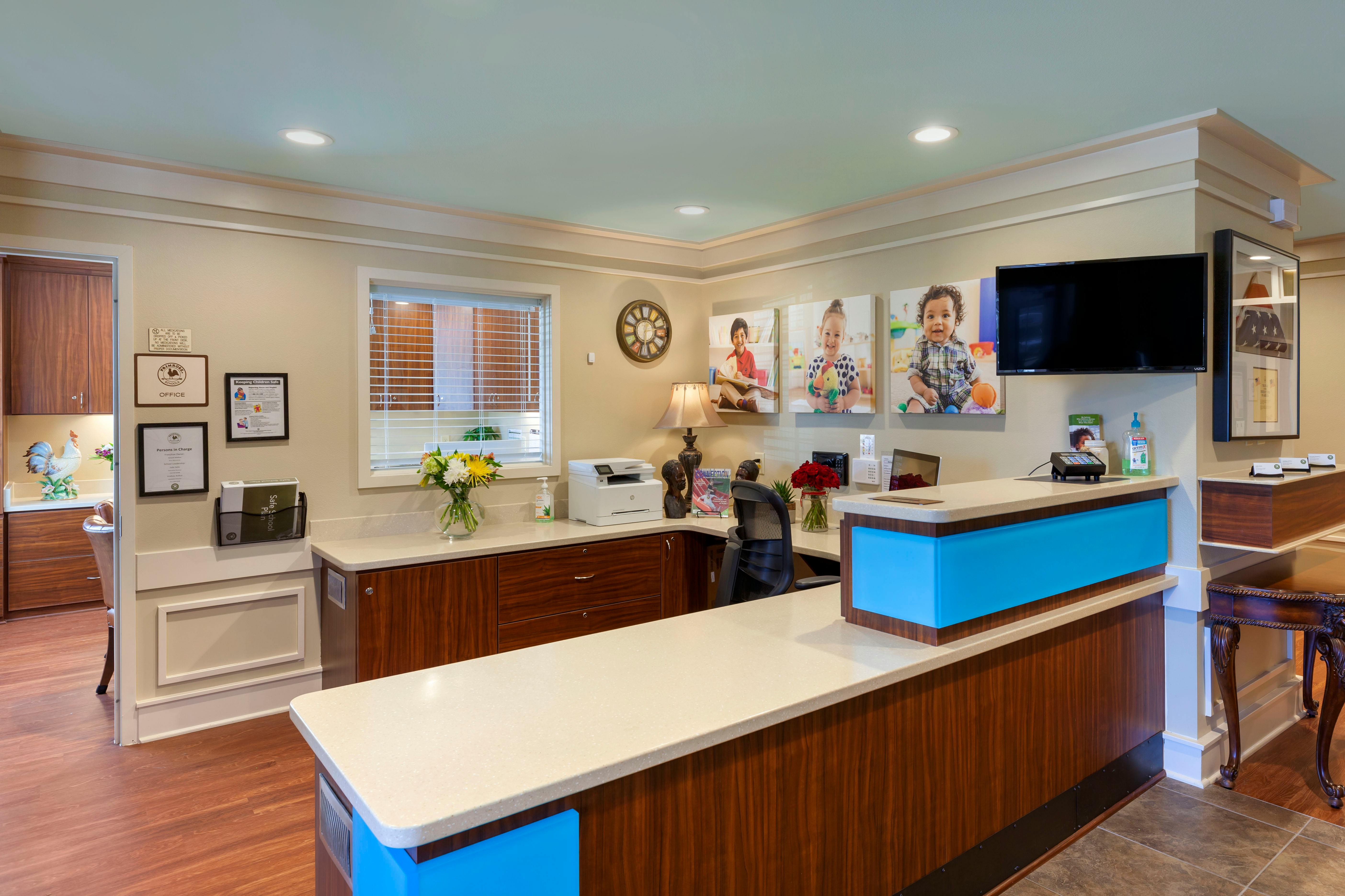 Reception desk with office signs, child portraits, and a printer