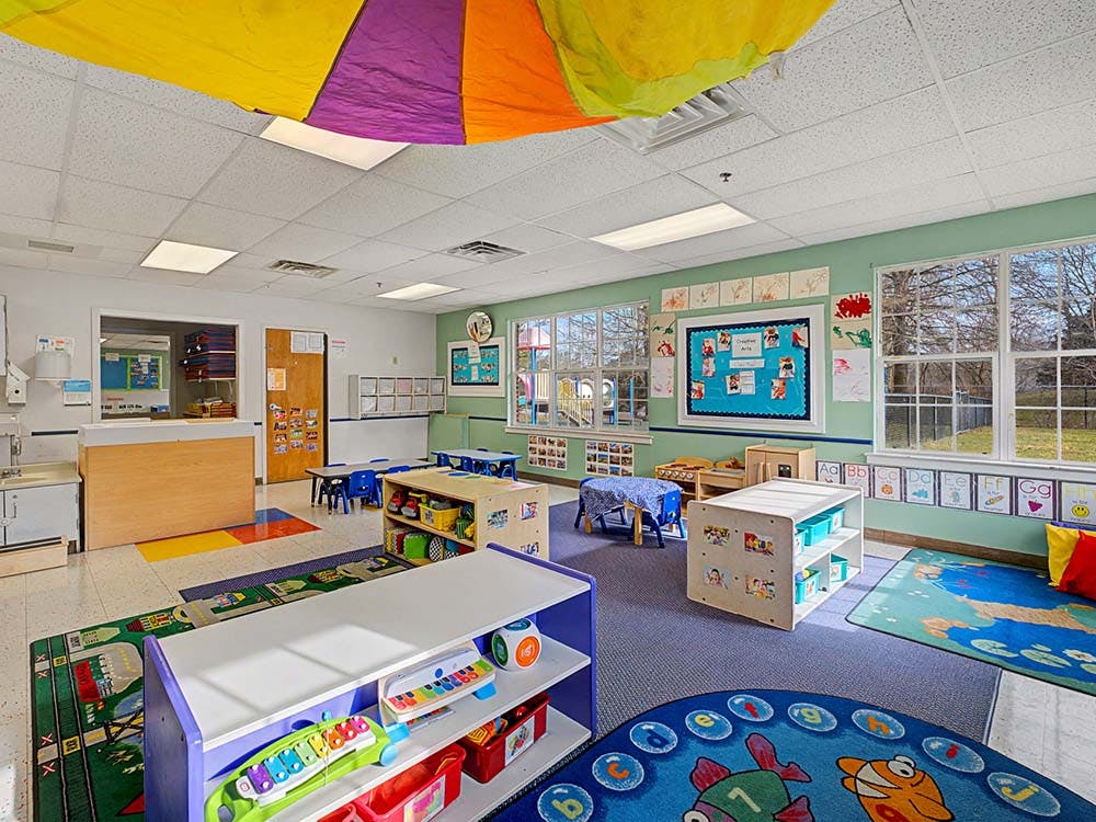 Colorful and organized preschool classroom with rugs, tables, and toys