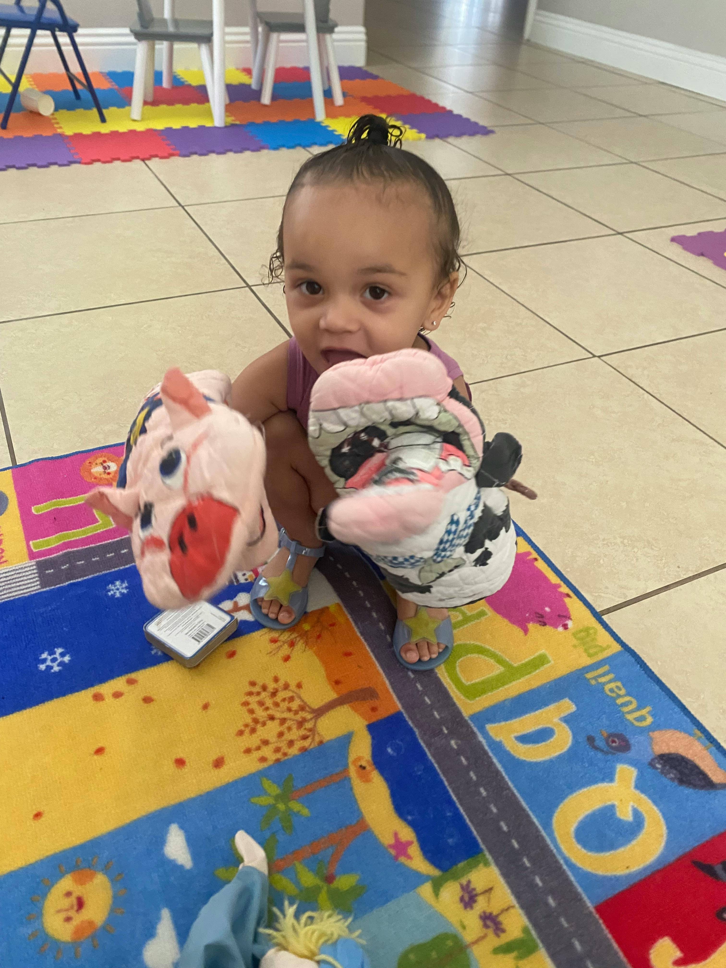 Child sitting on a colorful rug holding two stuffed animals