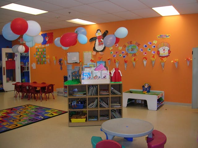 Classroom with orange walls, colorful decorations, small tables, and chairs