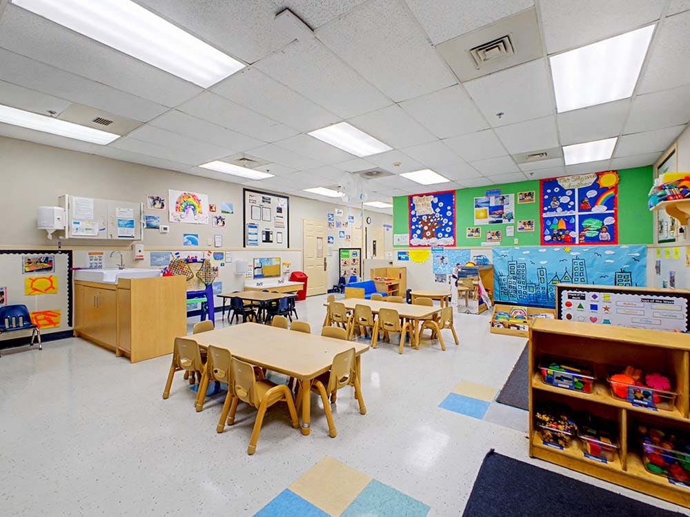 Empty children's classroom with small tables and chairs