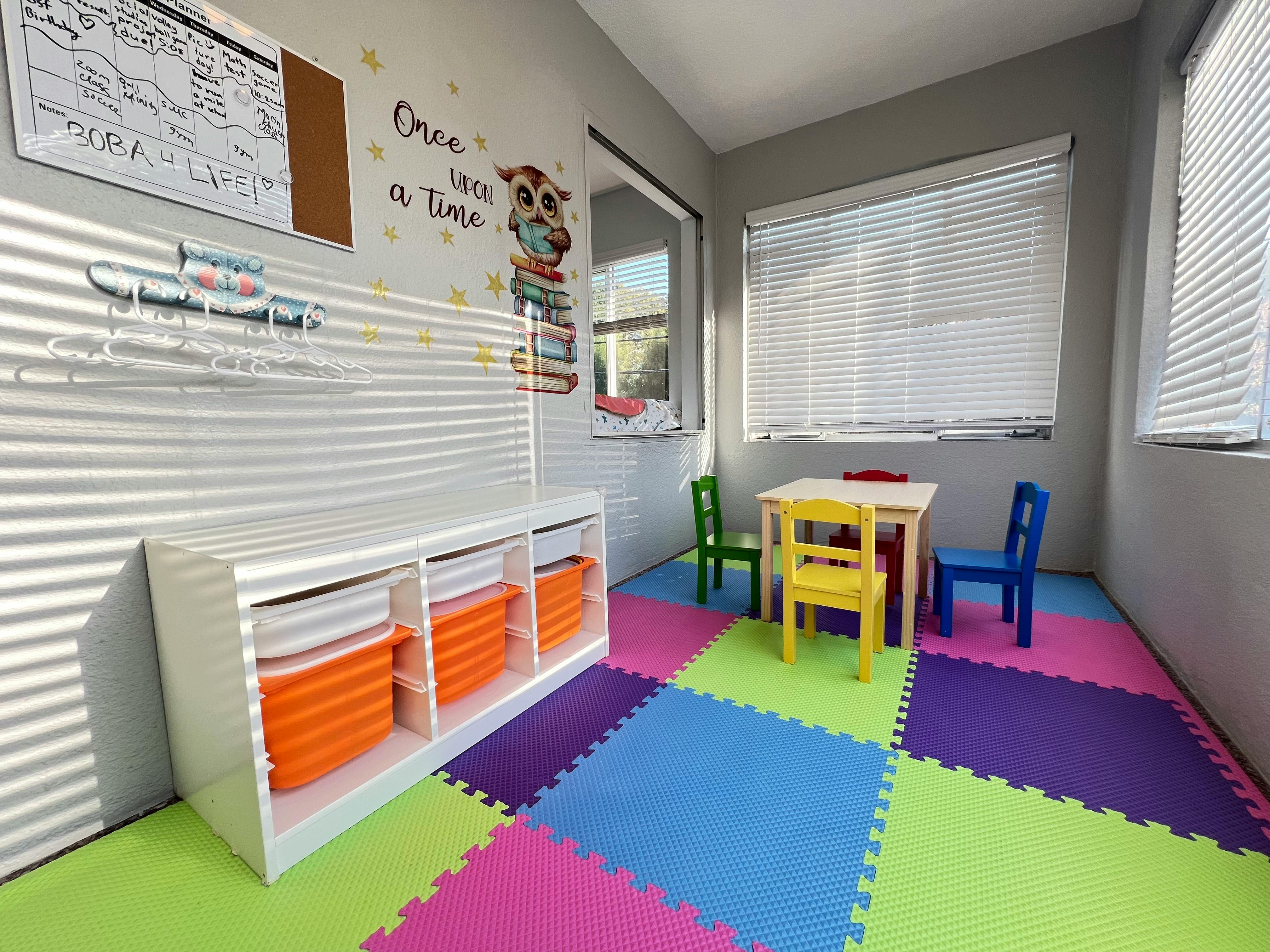 Playroom with colorful floor mats, small table and chairs, and storage unit
