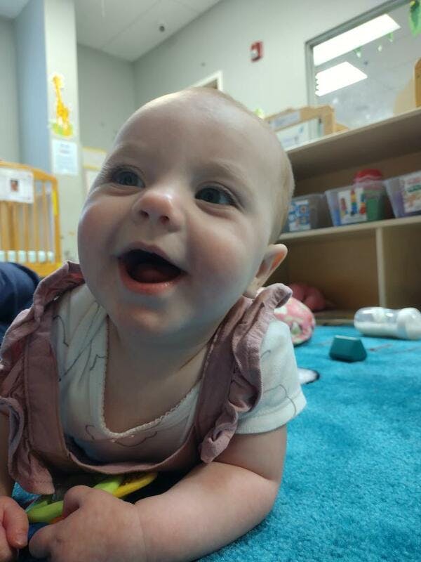 Child on a blue mat looking up with mouth open