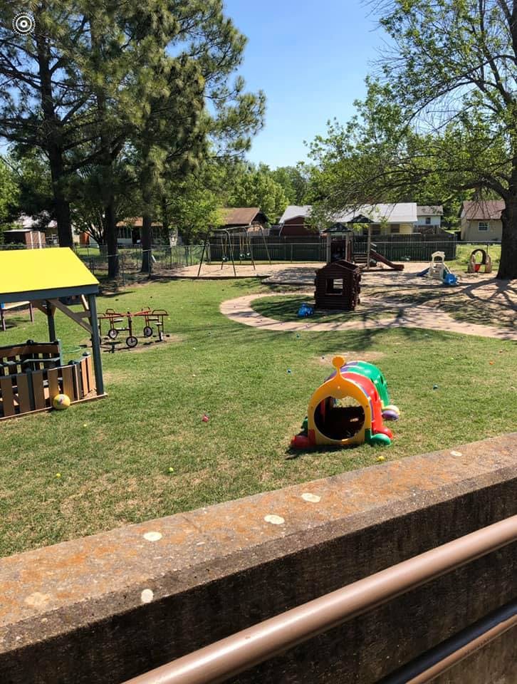 Outdoor playground with swings, slides, and a play tunnel on grass
