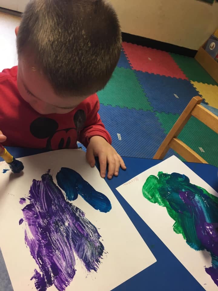 Child painting on paper with a brush