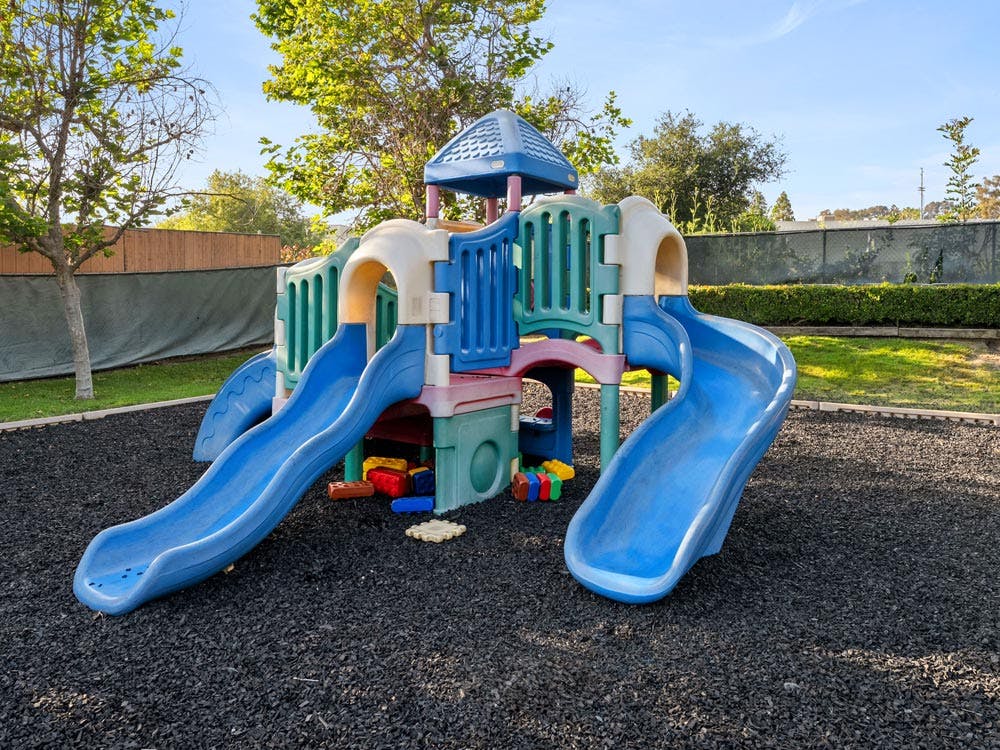 Colorful playground structure with multiple slides on a black rubber ground