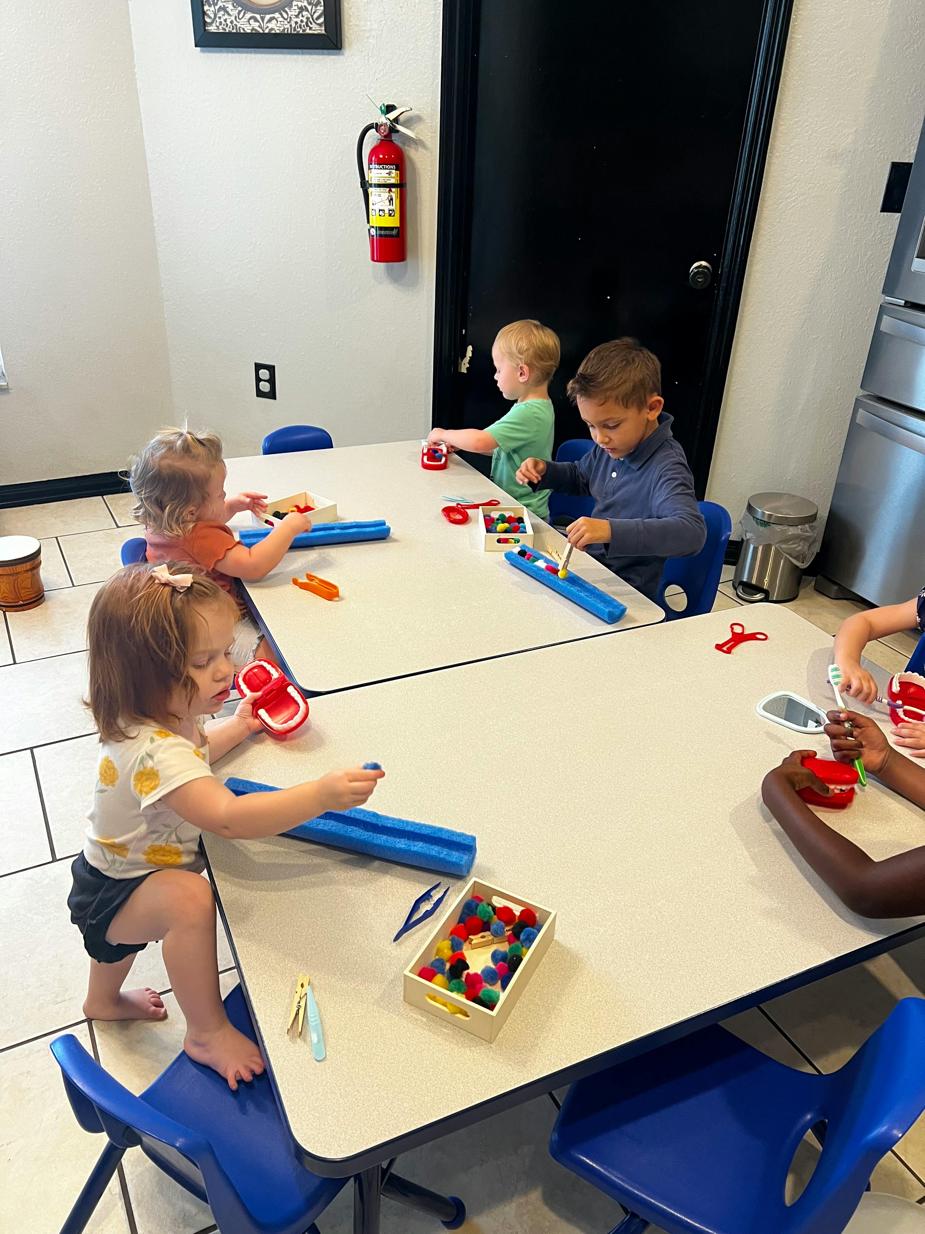 Children playing with toys at tables in a classroom