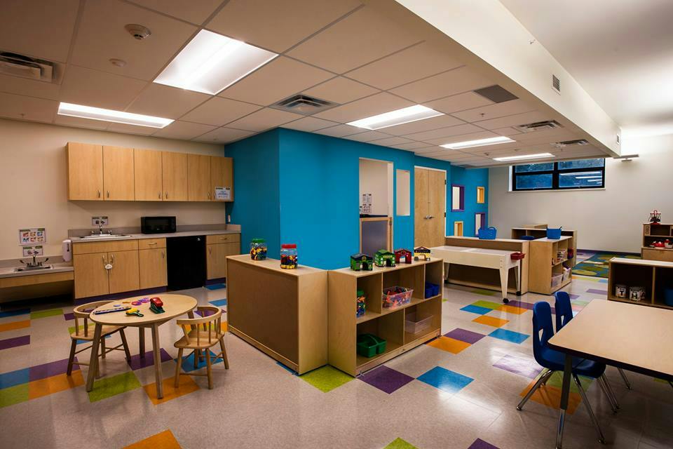 Classroom with colorful floor tiles, small tables, and storage shelves