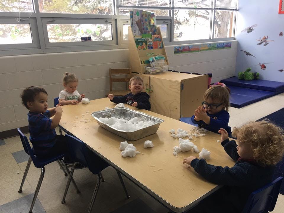Children playing with cotton balls at a table