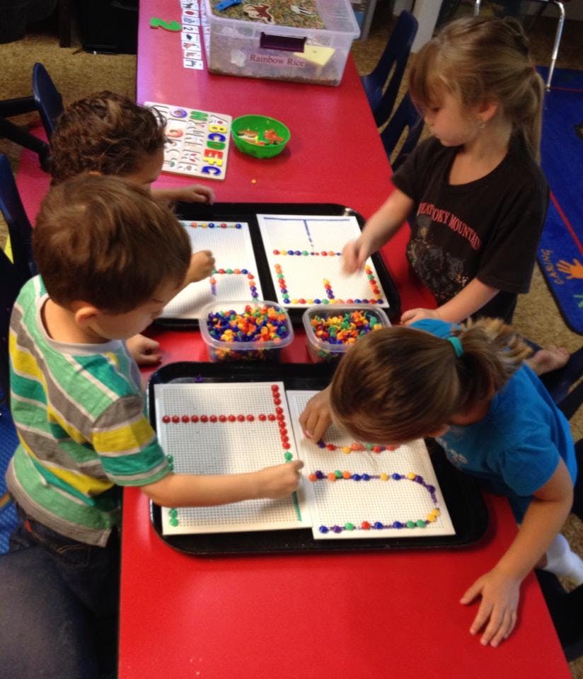 Children working on pattern activities with colorful beads at a table