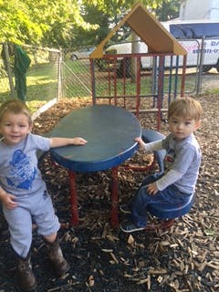 Two children sitting at a small table on a playground