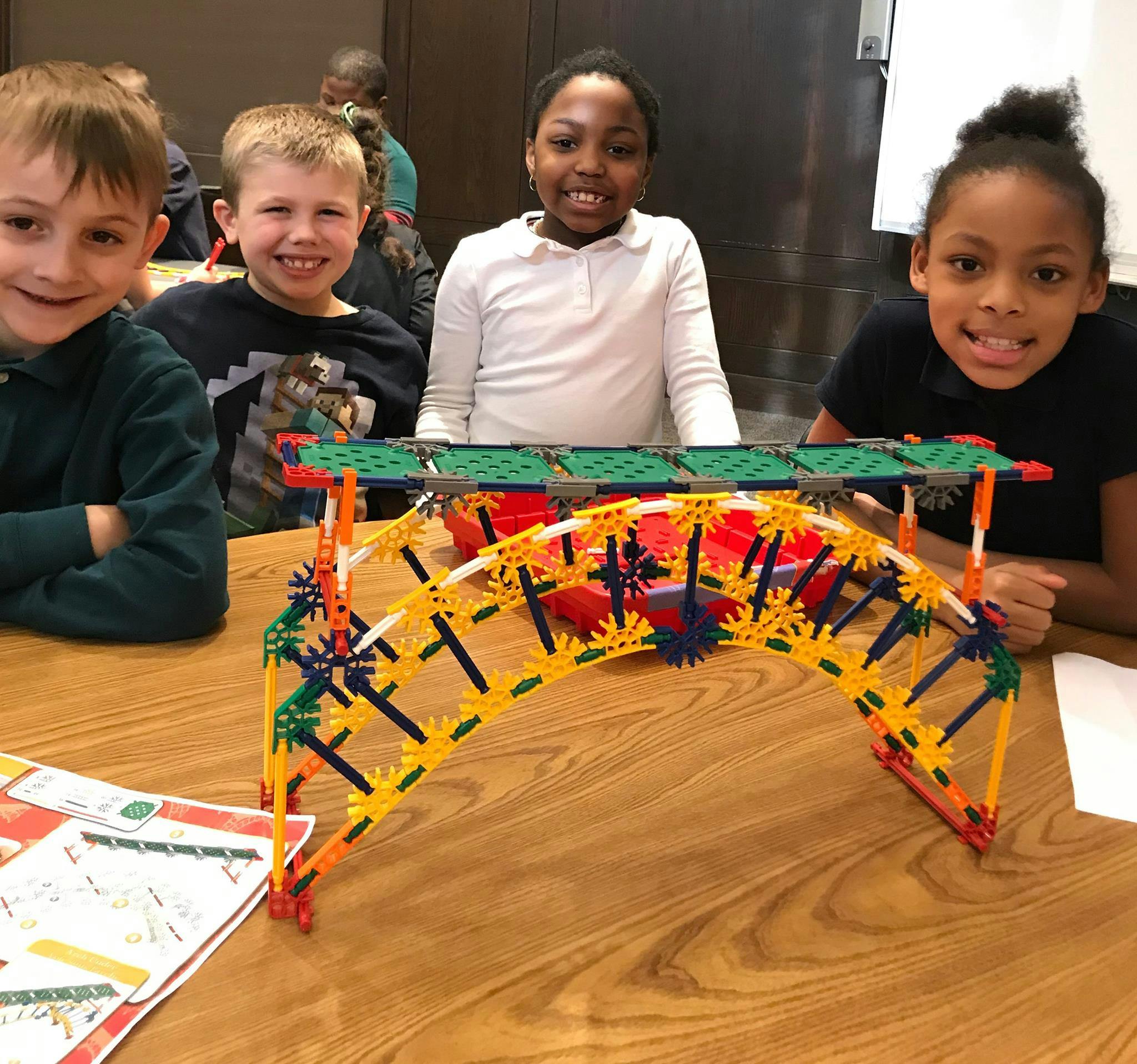 Four children with a K'nex bridge on a table