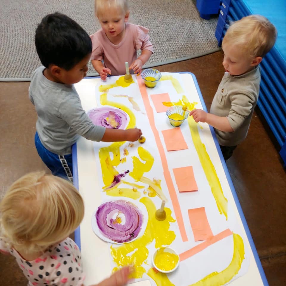 Four children painting at a table