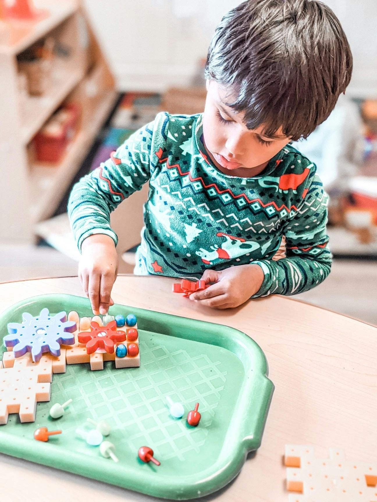 Child playing with building blocks on a green tray
