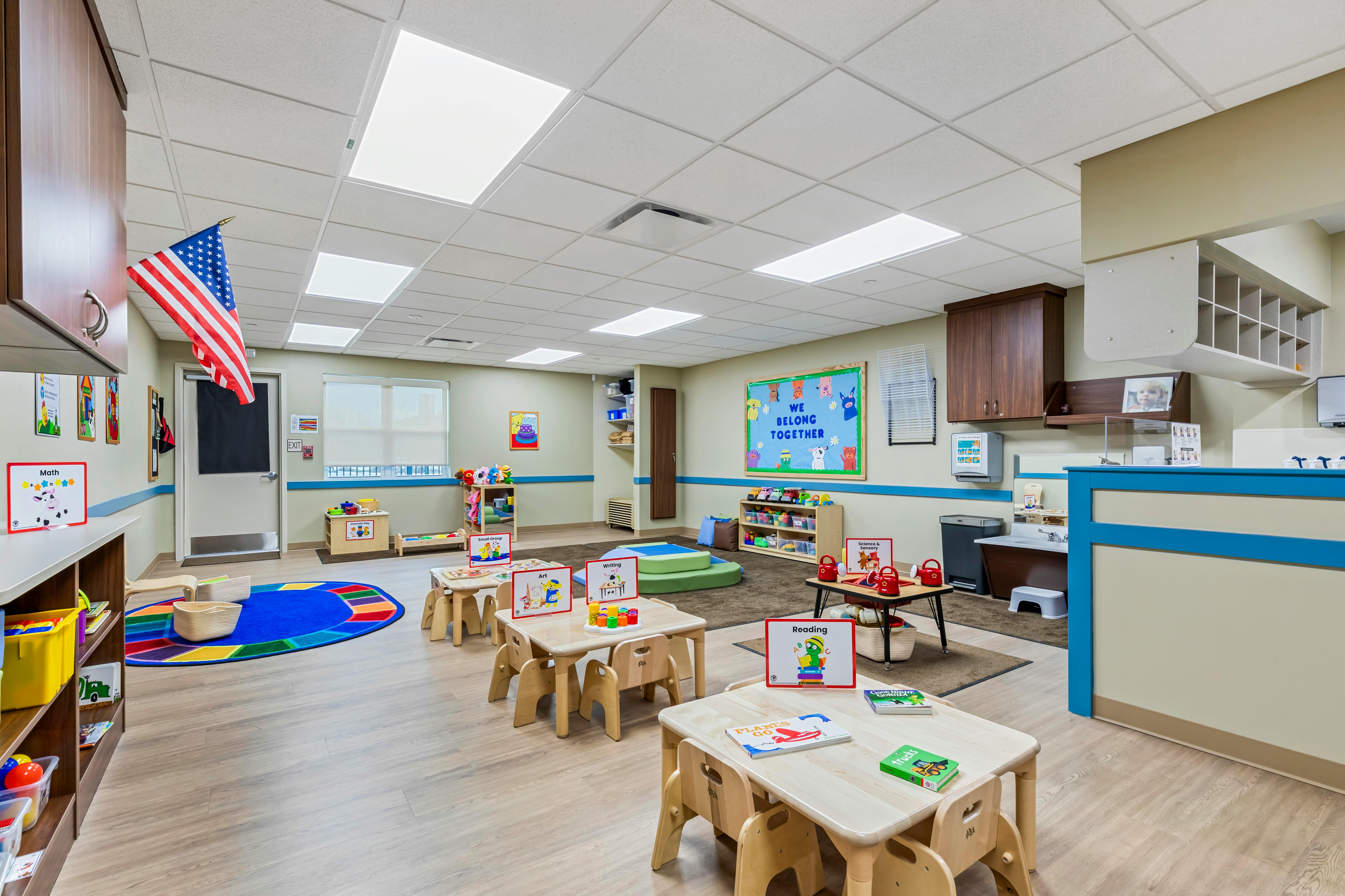 An empty early childhood classroom with small tables and chairs