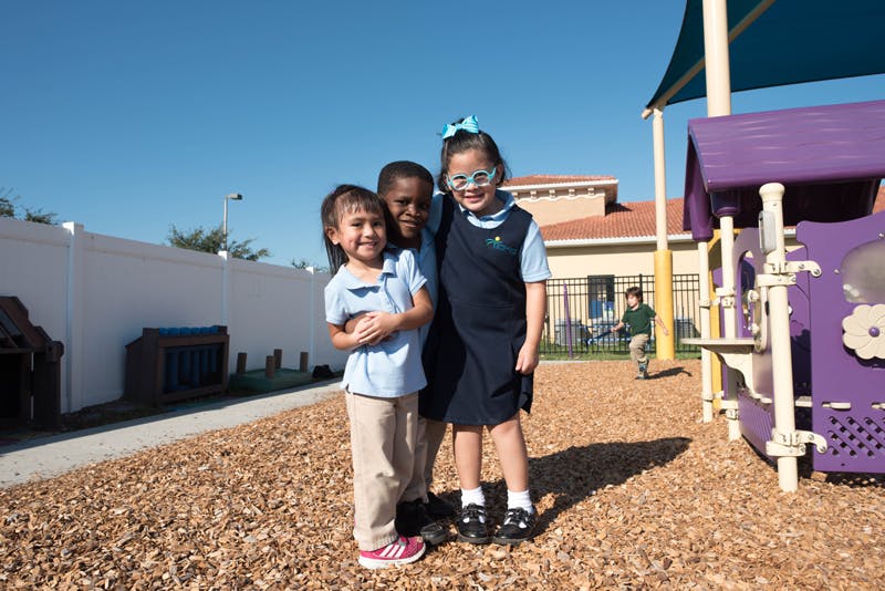 Three children standing together on a playground