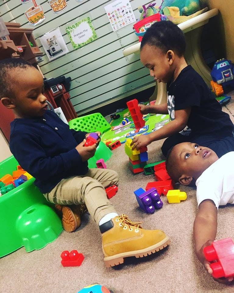 Three children playing with colorful building blocks on the floor