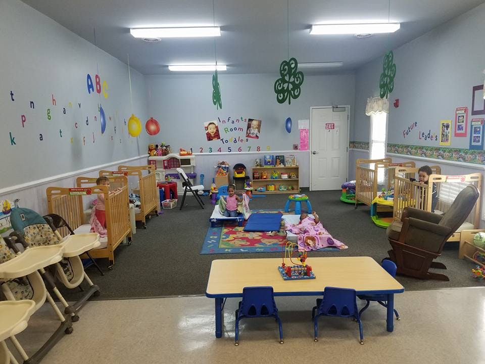 Daycare room with cribs, high chairs, and play areas