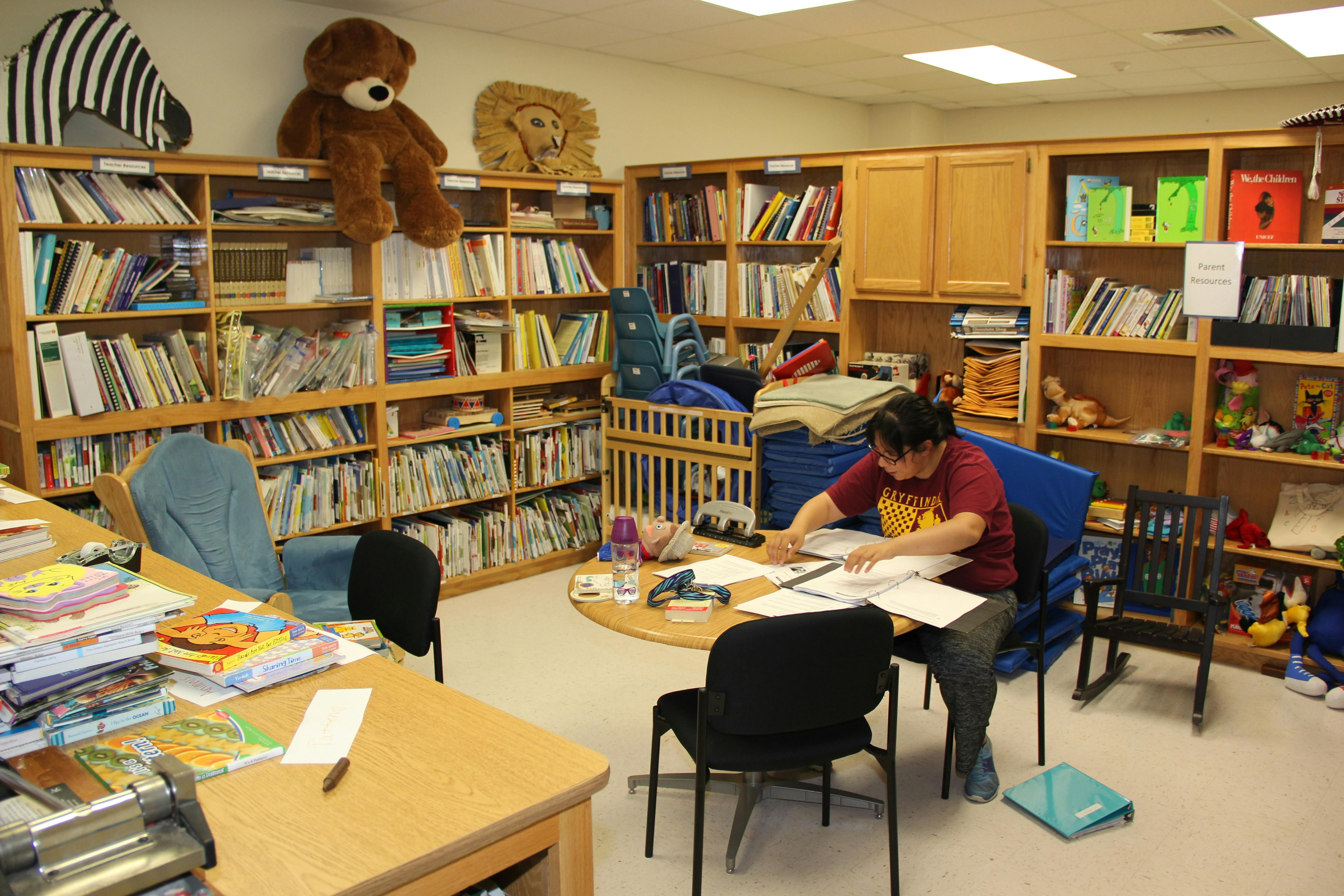 Person working at a table in a room with bookshelves