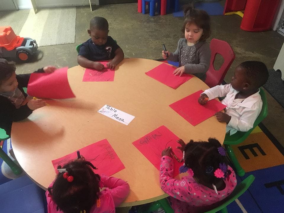 Children sitting around a table with red papers