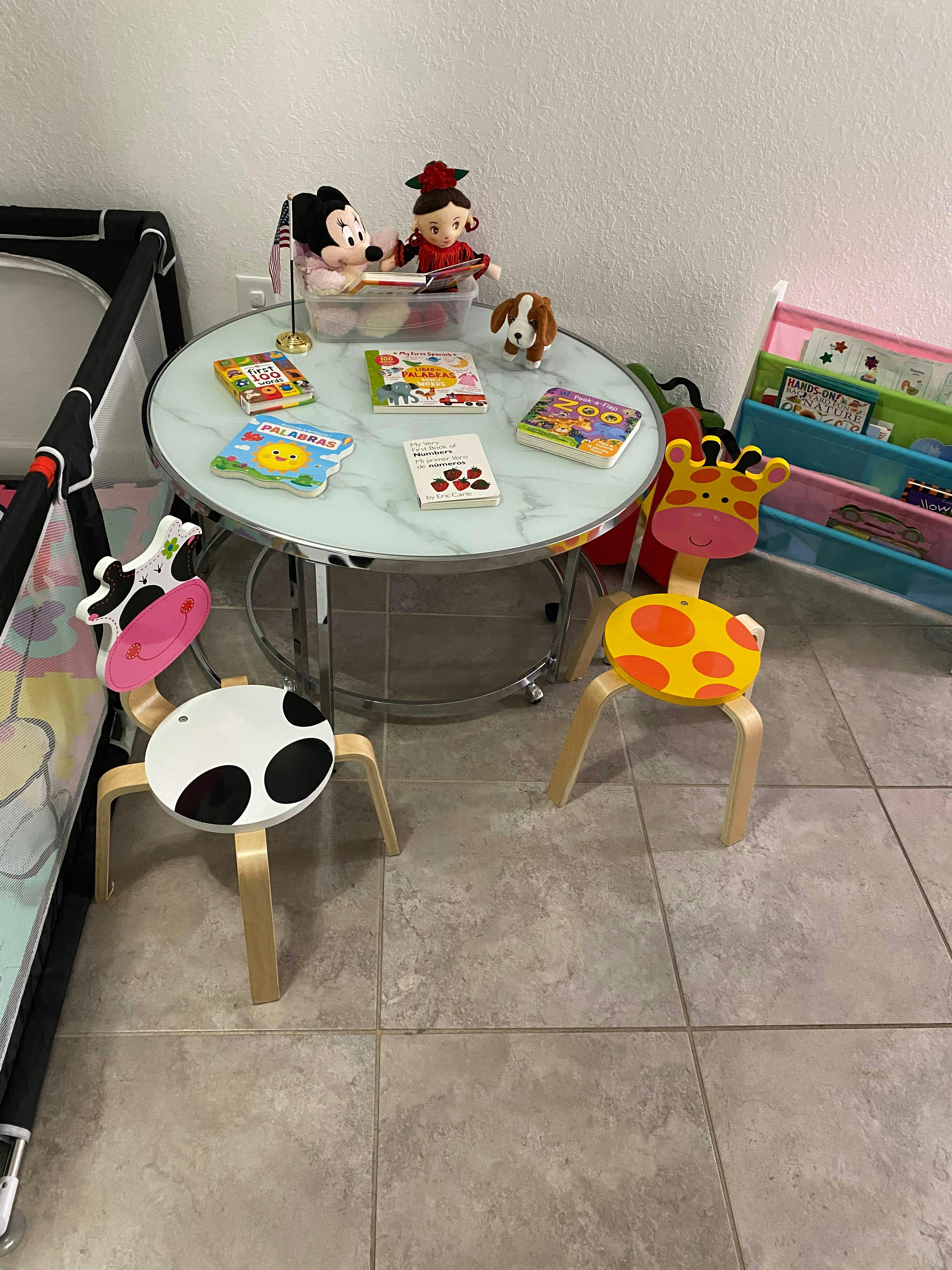 Children's table with books and toys, two animal-themed chairs