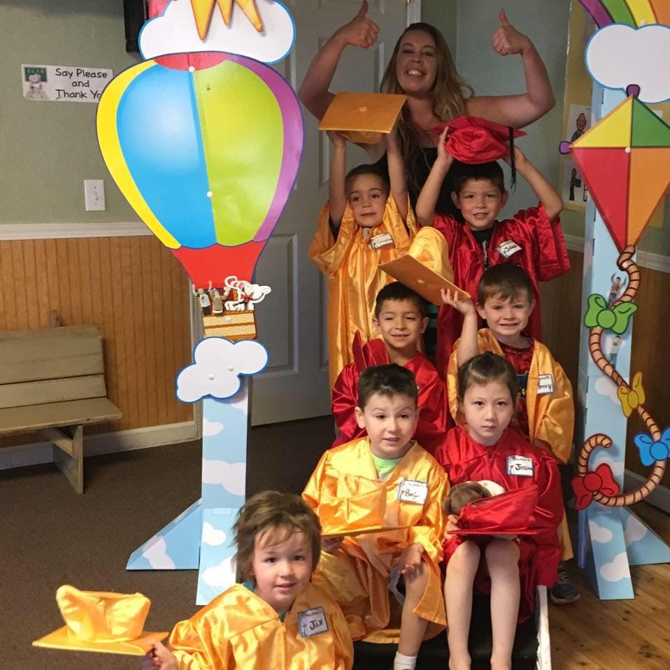 Adult and children in graduation gowns posing with cutouts