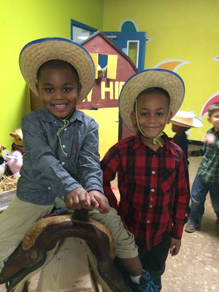 Two children in straw hats, one sitting on a saddle
