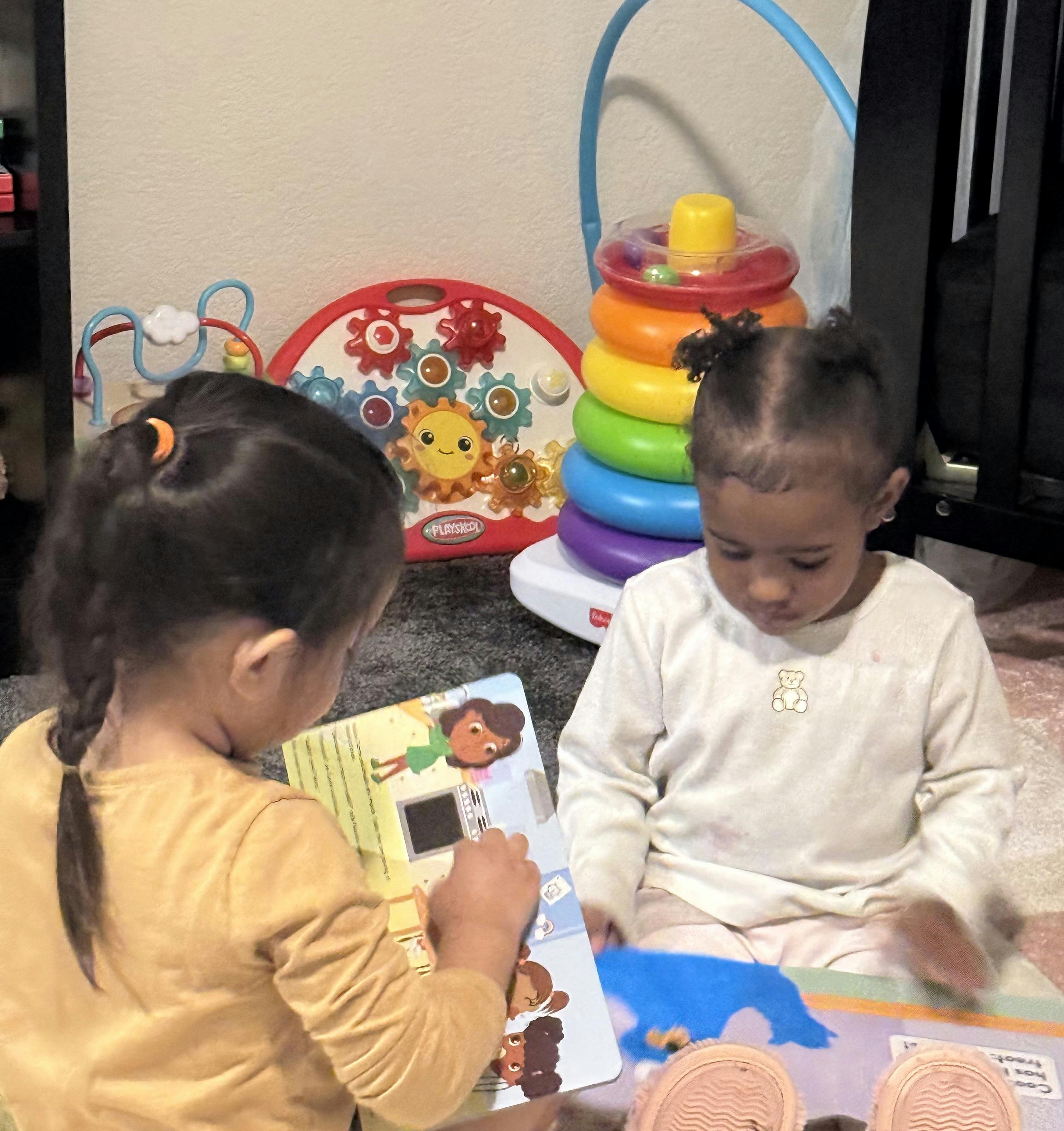 Two children sitting on the floor reading a book together
