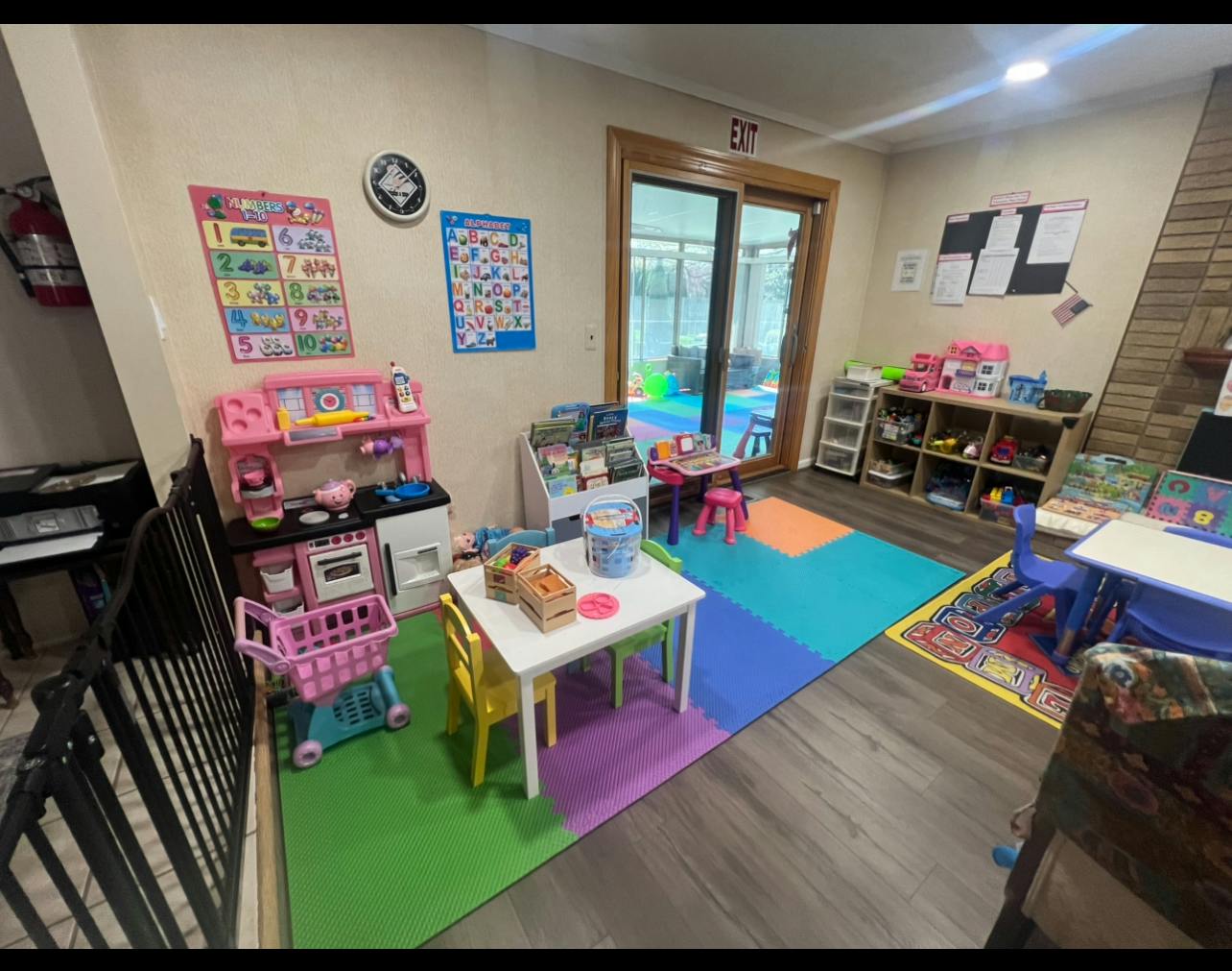 children's playroom with colorful mats, play kitchen, and small tables with chairs