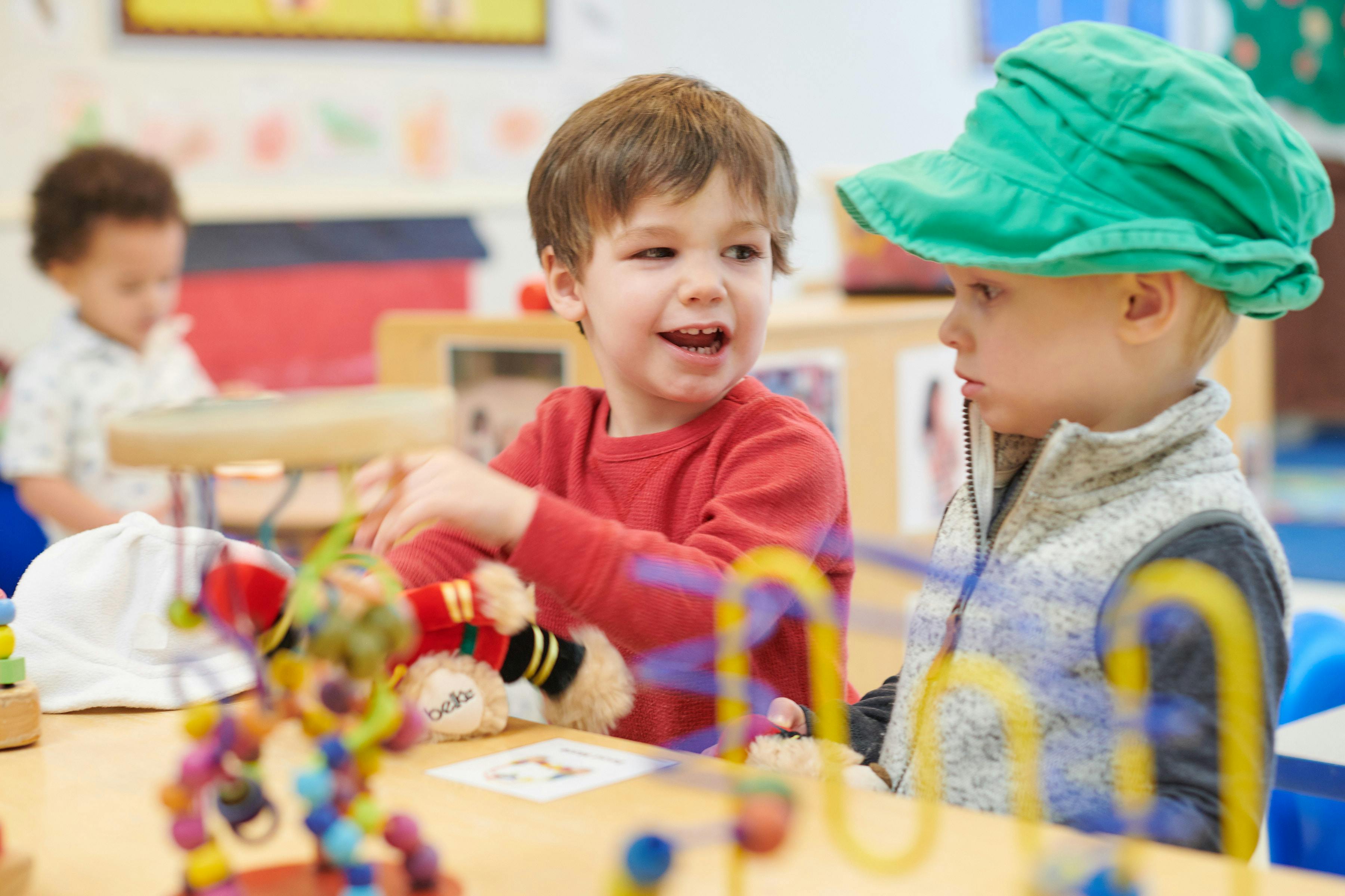 Two children playing with toys at a table in a classroom