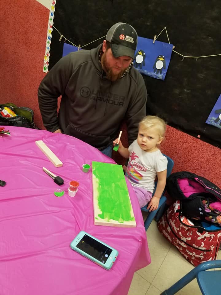 Person and child painting a board green