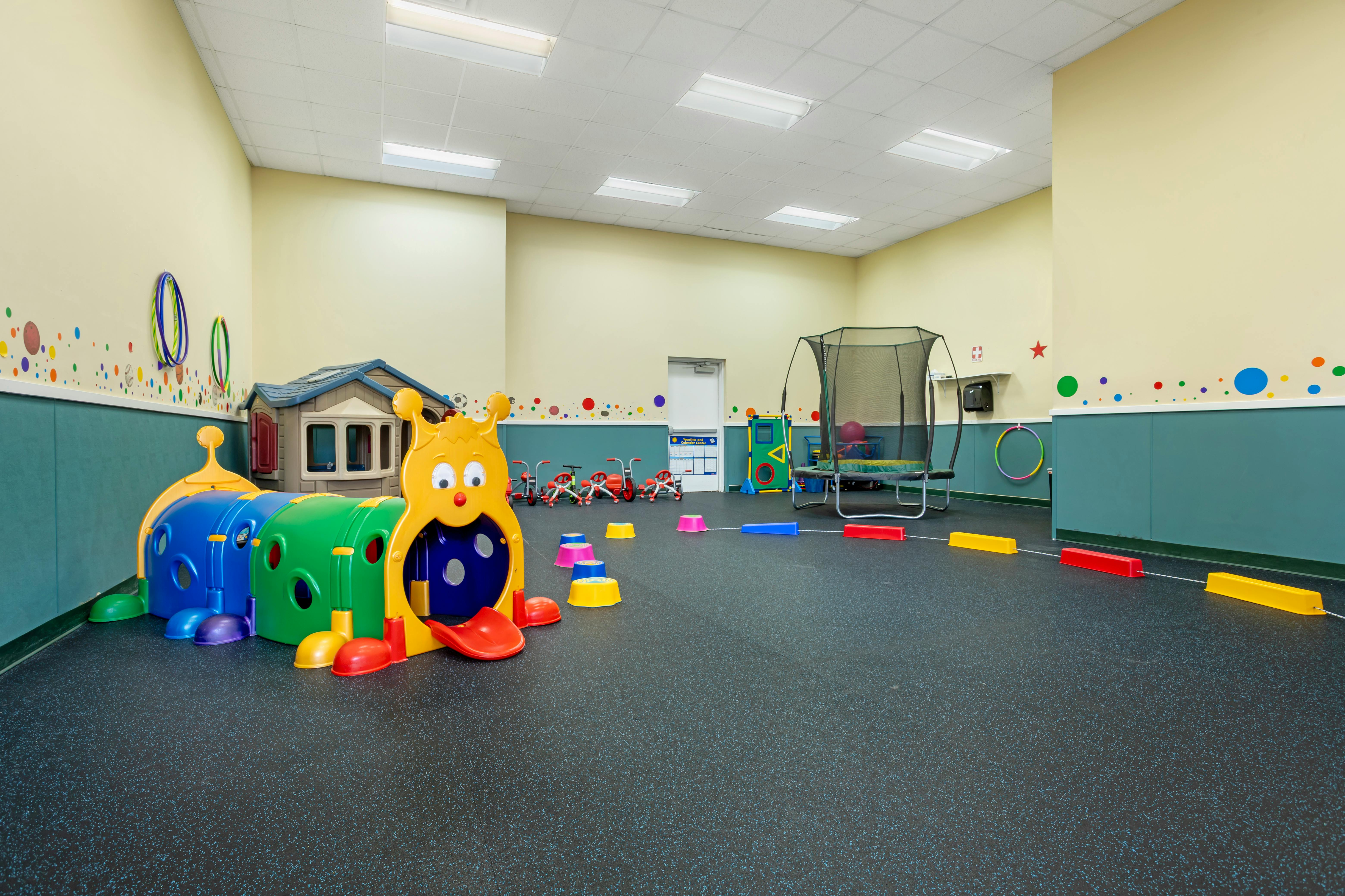 Indoor play area with colorful caterpillar tunnel and small trampoline