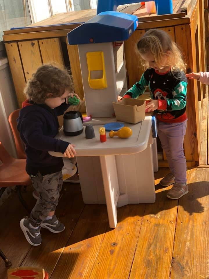 Two children playing with a toy kitchen set