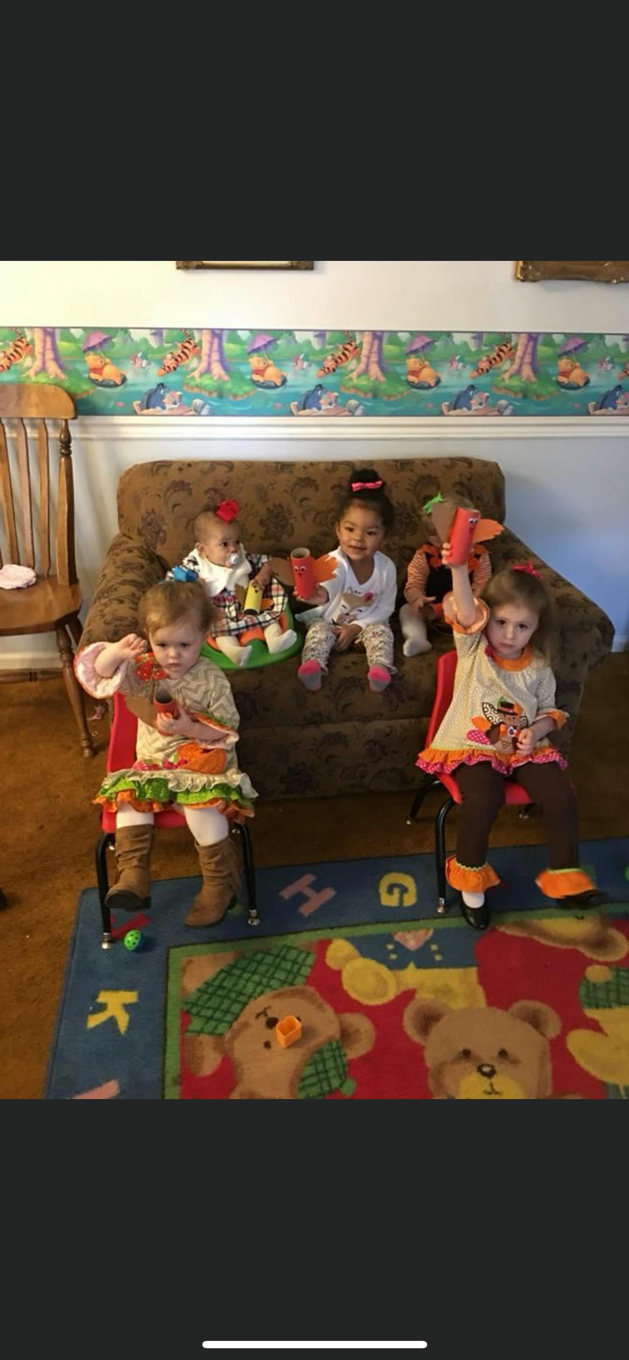Four children and two babies sitting on a couch and chairs