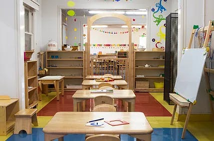 Empty classroom with small wooden tables and chairs