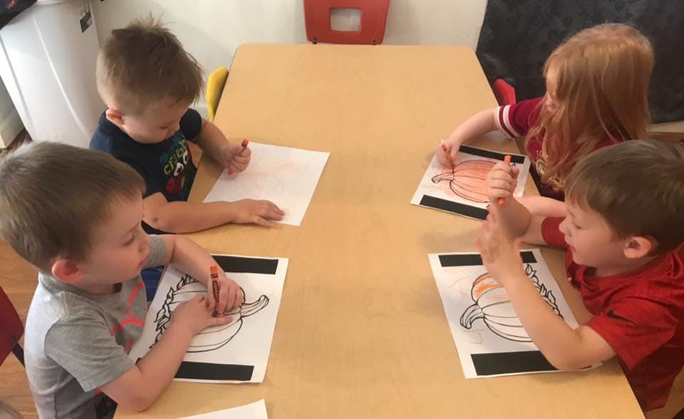Four children coloring at a table