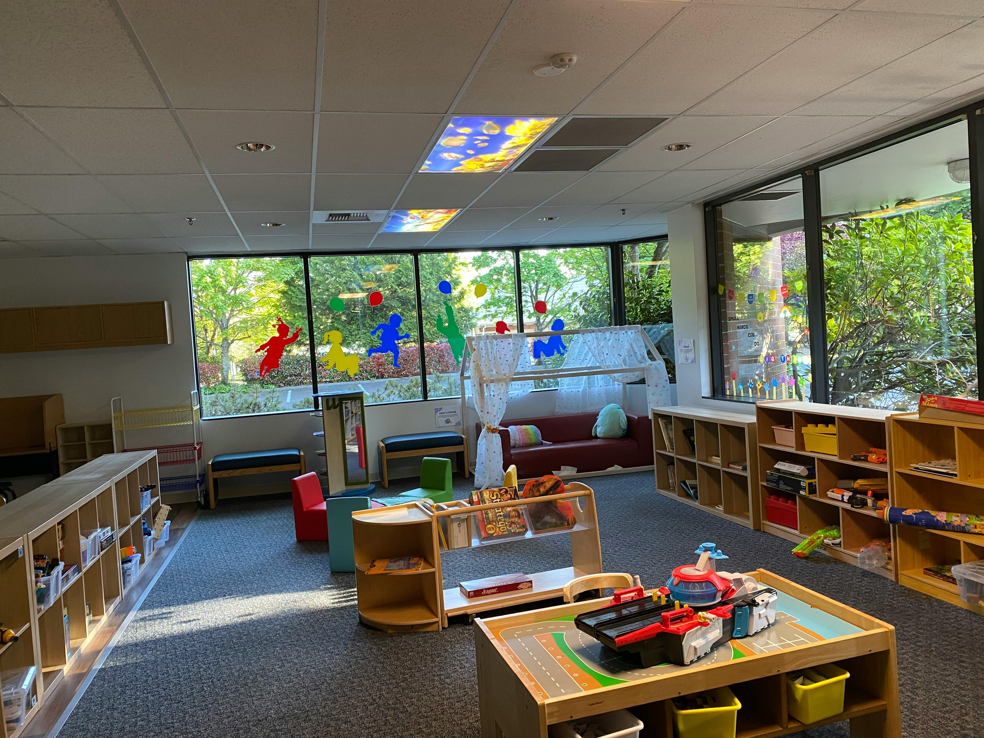 Classroom with toy shelves, play table, colorful decorations, and large windows