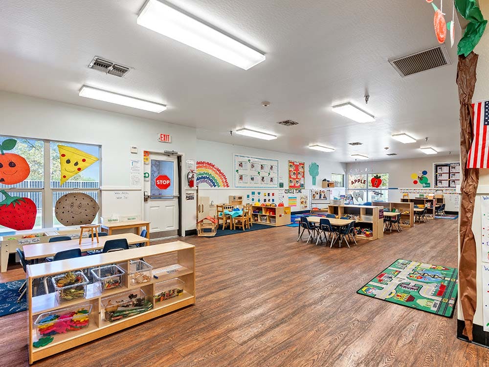 Empty classroom with small tables, chairs, and colorful decorations
