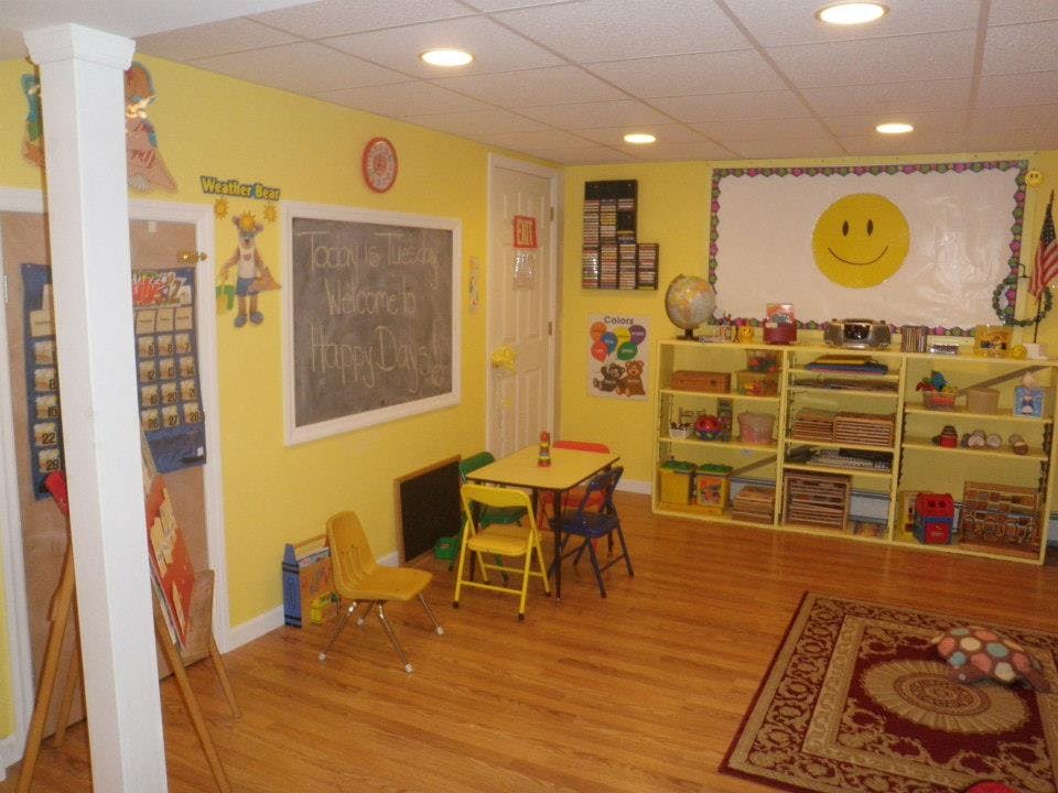 Classroom with yellow walls, small table and chairs, and shelves with toys