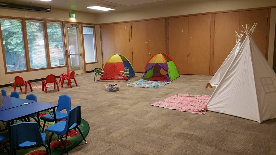Playroom with small tables and chairs, colorful tents, and a teepee